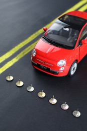 Pins as barrier blocking way for red toy car. Development through obstacles overcoming