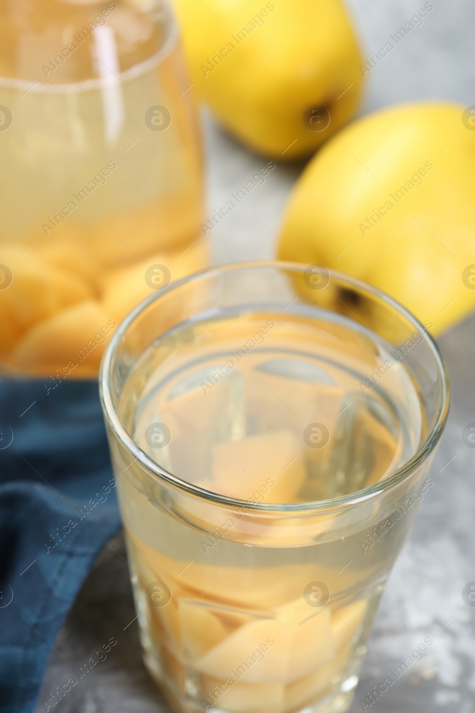 Photo of Delicious quince drink and fresh fruits on grey table, closeup