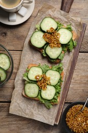 Photo of Tasty cucumber sandwiches with arugula and mustard on wooden table, flat lay