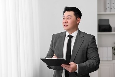 Photo of Portrait of happy notary with clipboard indoors, space for text