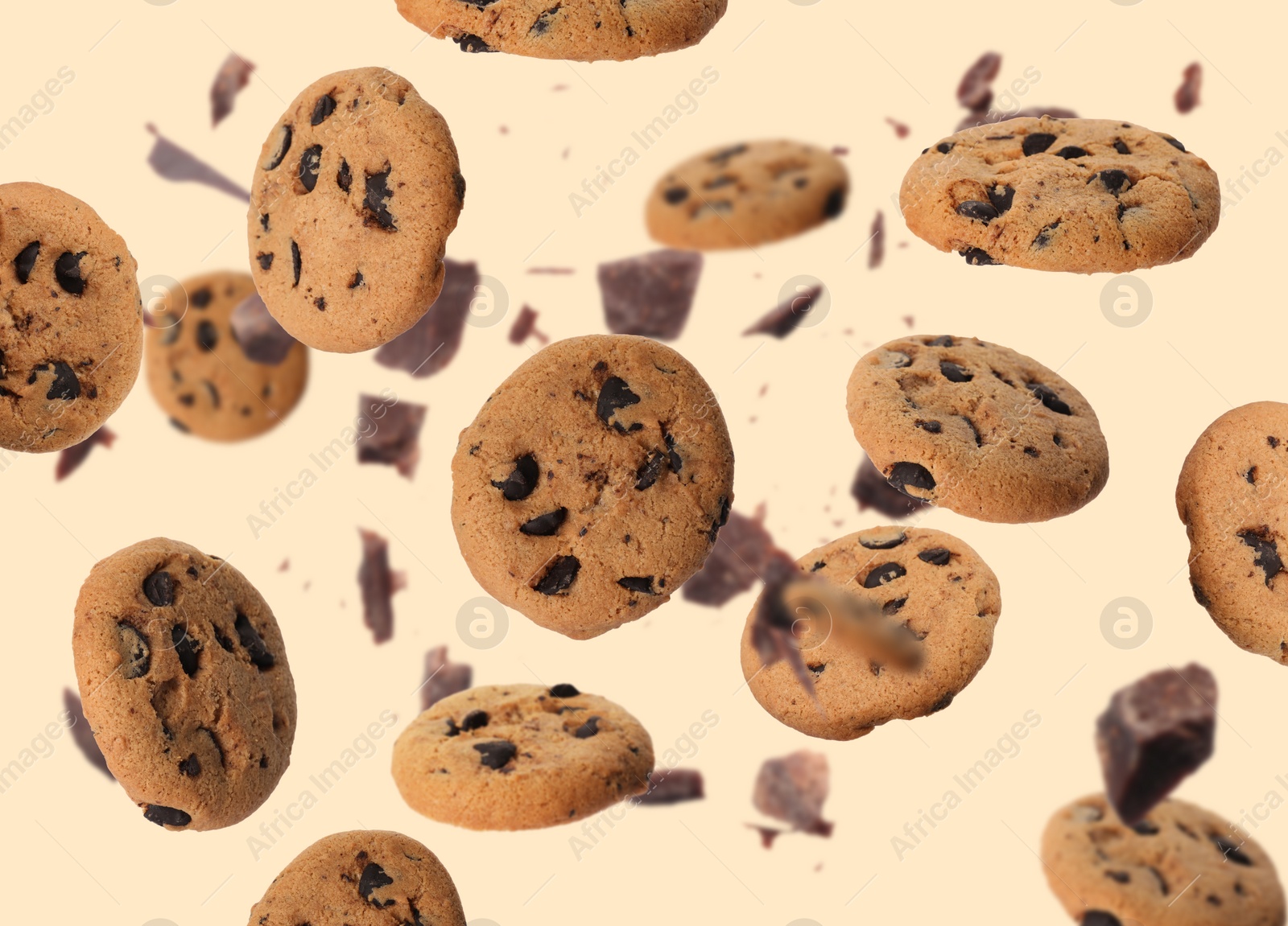 Image of Delicious chocolate chip cookies and pieces of chocolate falling on beige background