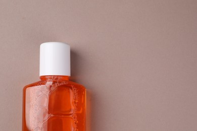 Photo of Fresh mouthwash in bottle on beige background, top view. Space for text