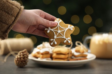 Woman with decorated Christmas cookie at table, closeup