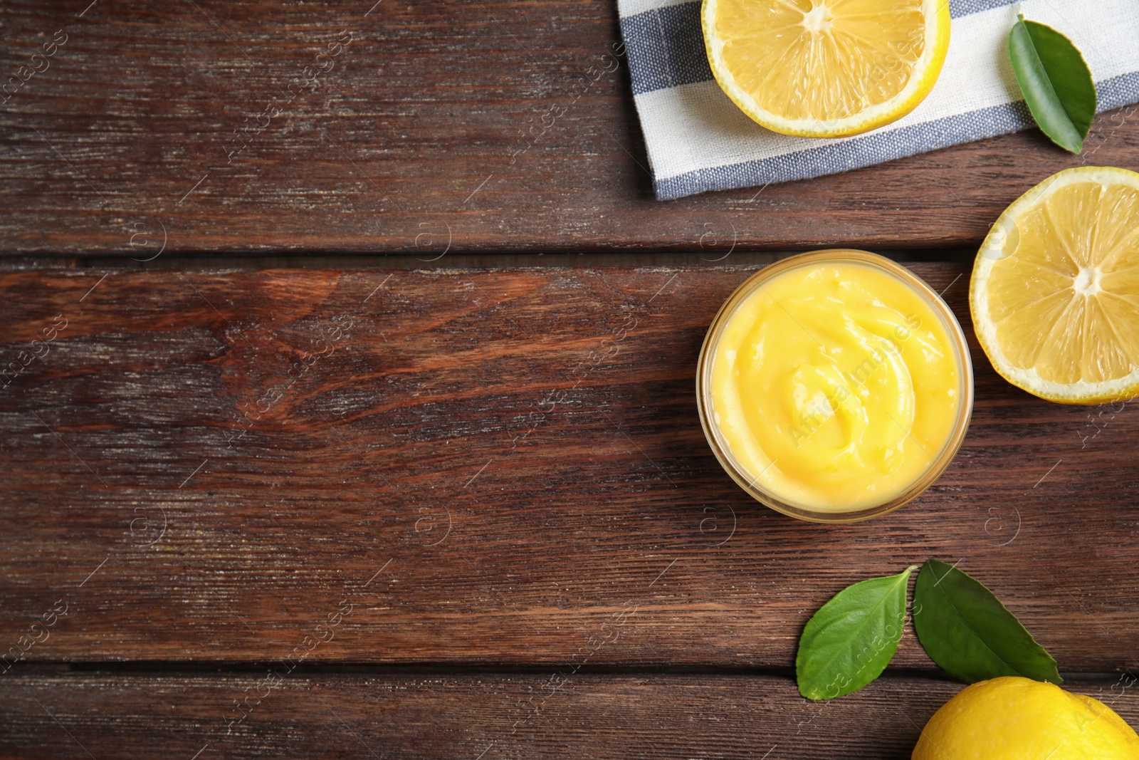 Photo of Delicious lemon curd in bowl on wooden table, flat lay. Space for text