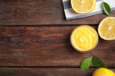 Delicious lemon curd in bowl on wooden table, flat lay. Space for text