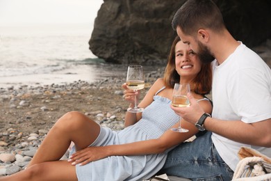 Photo of Happy young couple having picnic on beach near sea. Space for text