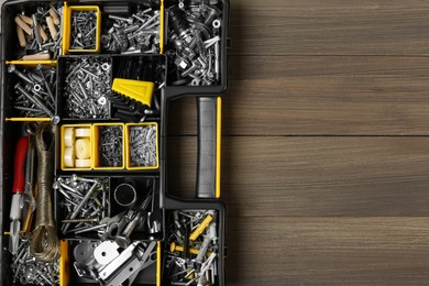 Photo of Box with different furniture fittings and tools on wooden table, top view. Space for text