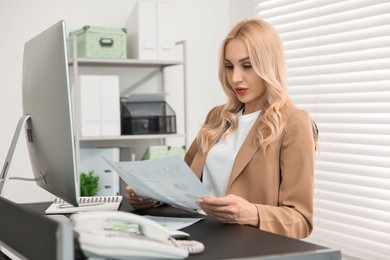 Secretary working with documents at table in office