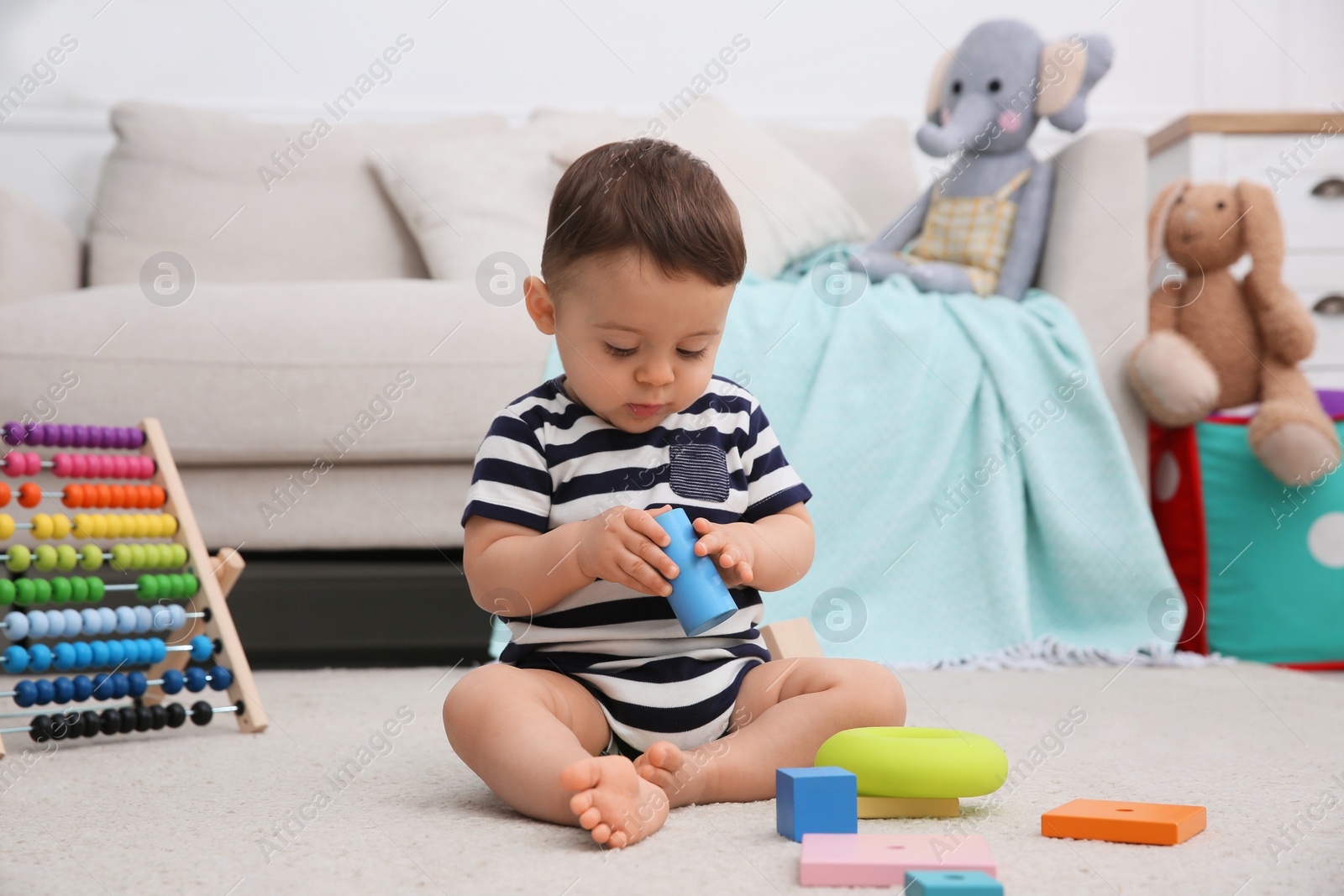 Photo of Cute baby boy playing with toys on floor at home