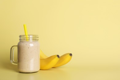 Photo of Mason jar with tasty smoothie and bananas on beige background. Space for text