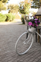 Photo of Retro bicycle with flowers in basket on outdoor terrace