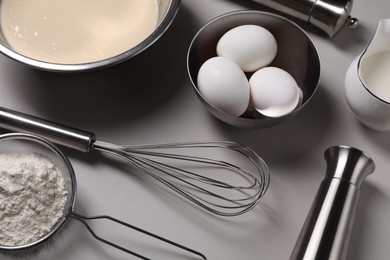 Photo of Composition with whisk and dough in bowl on grey background