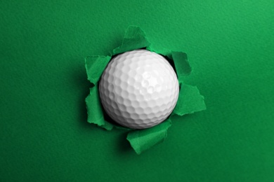Photo of Torn color paper with golf ball. Sport equipment