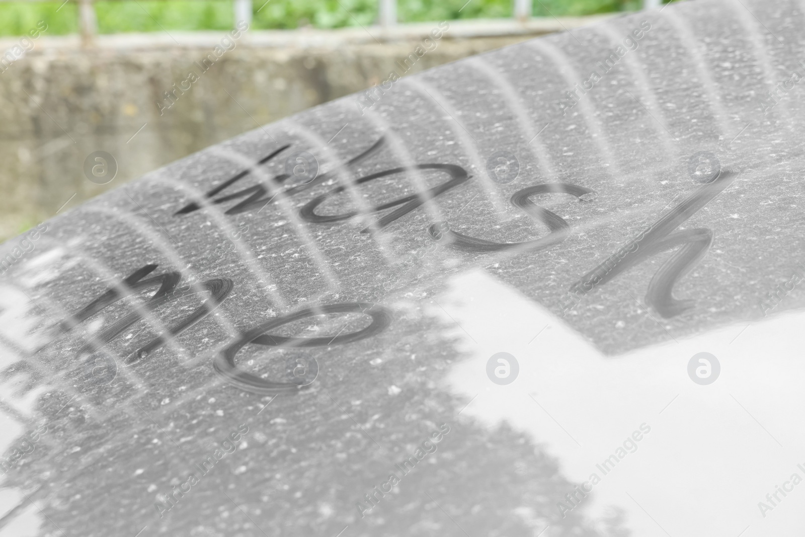 Photo of Phrase Wash Me written on dirty car outdoors, closeup