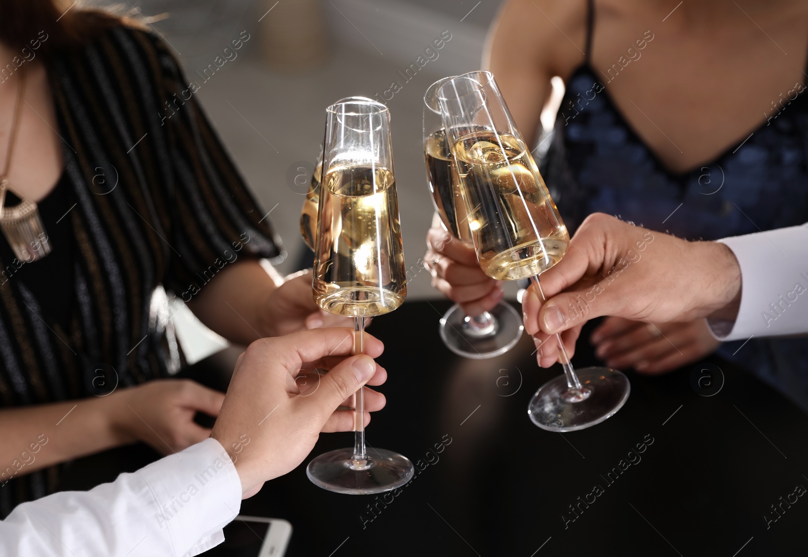 Photo of Friends clinking glasses of champagne in restaurant, closeup