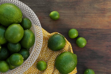 Photo of Fresh ripe limes on wooden table, flat lay. Space for text