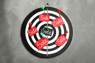Photo of Sale tags pinned to target with arrows on grey wall. Black Friday concept
