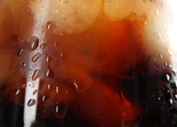 Photo of Glass of tasty refreshing cola with ice cubes, closeup