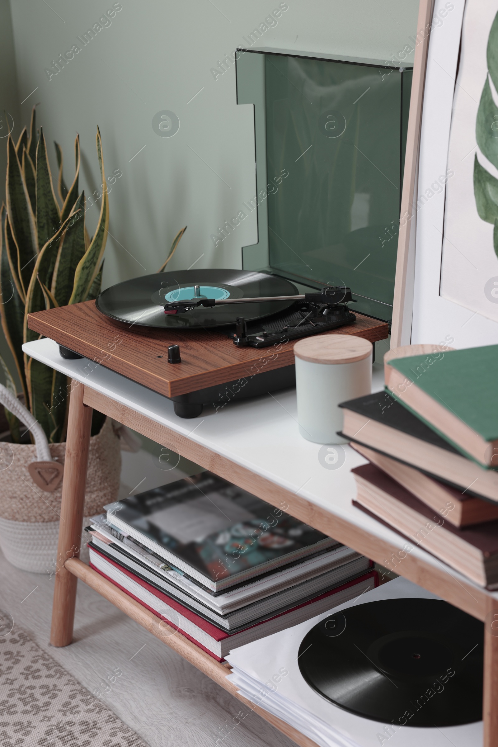 Photo of Stylish turntable with vinyl record on console table in room