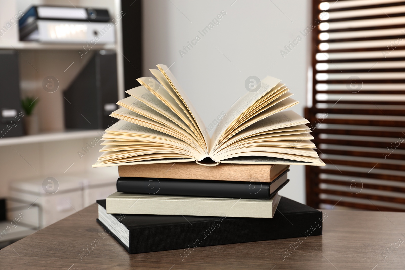 Photo of Stack of different hardcover books on wooden table indoors