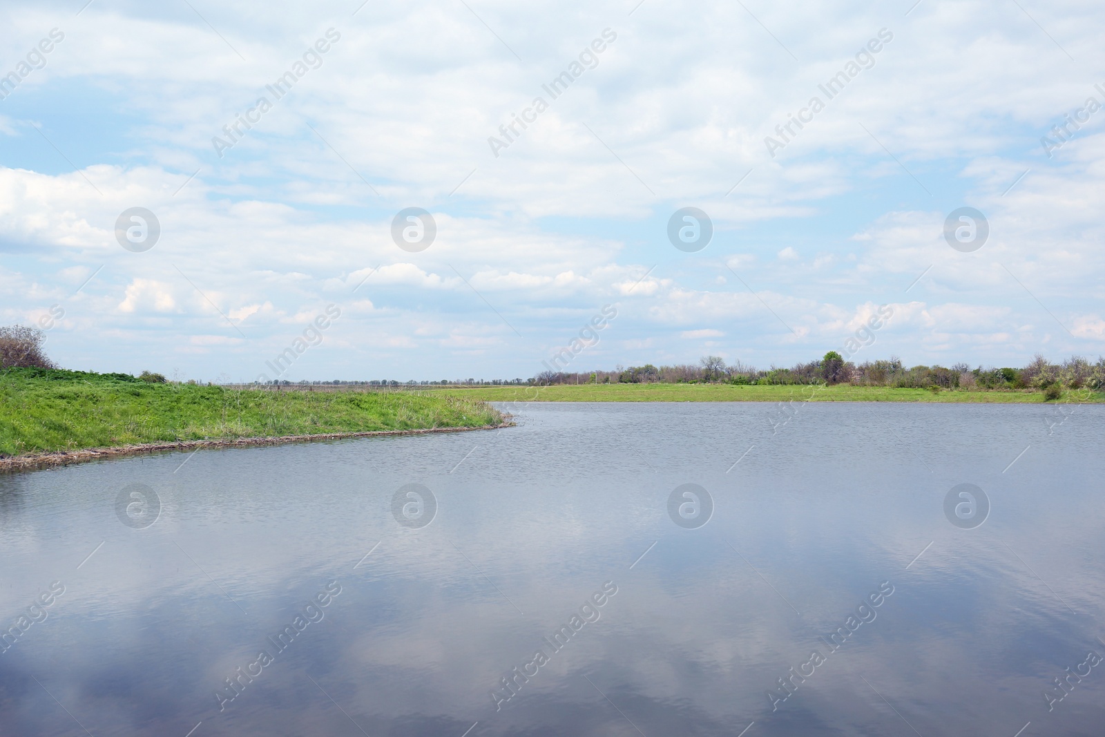 Photo of River near village under sky with clouds. Picturesque landscape