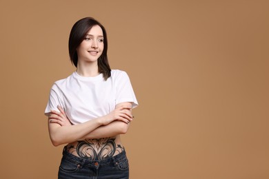 Portrait of smiling tattooed woman on beige background. Space for text