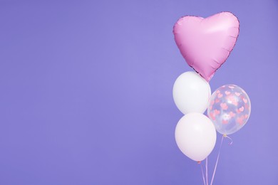 Photo of Bunch of heart and round shaped balloons on violet background, space for text. Birthday party