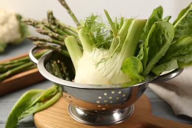 Metal colander with fennel, lettuce and asparagus on table, closeup