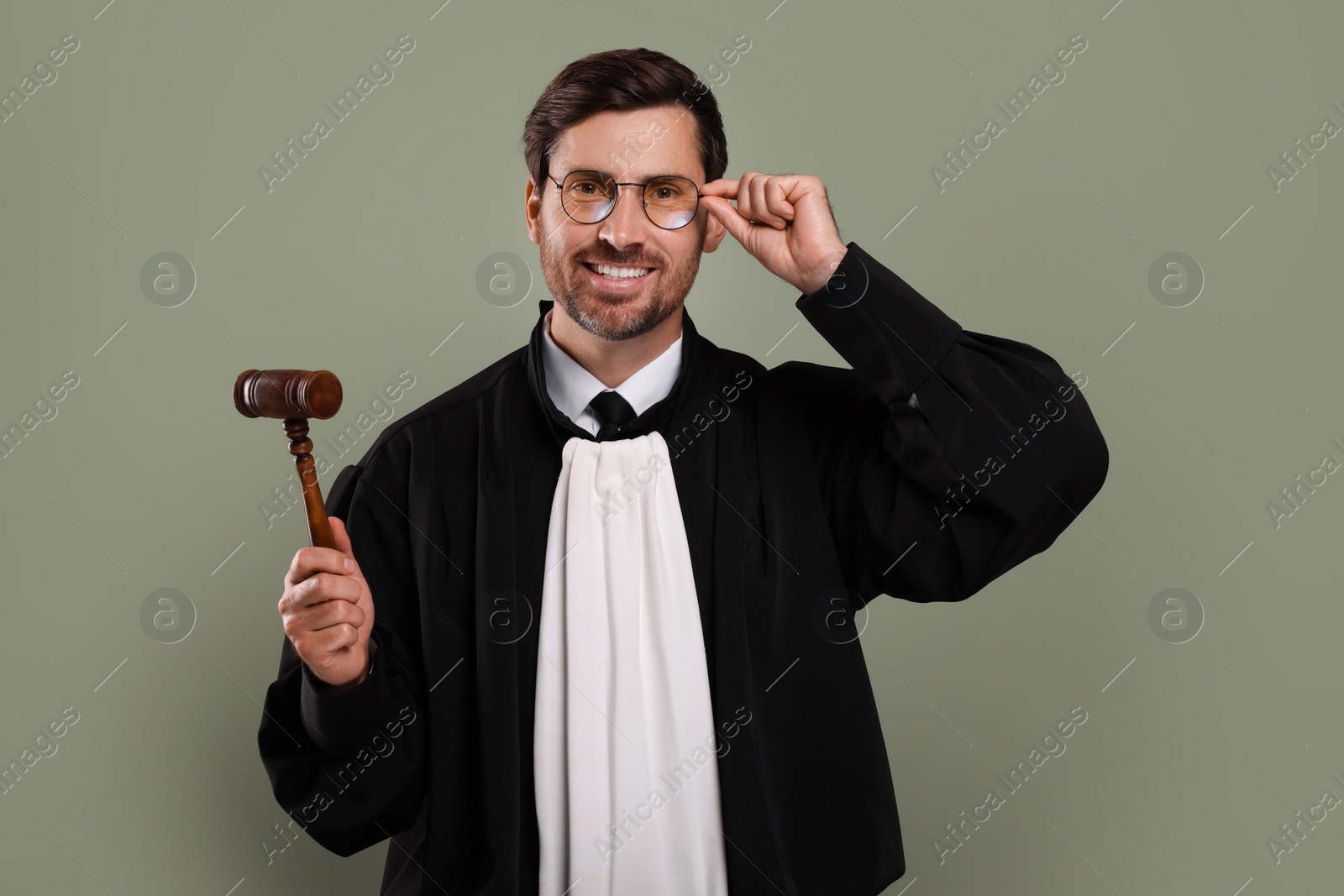 Photo of Happy judge with gavel on green background