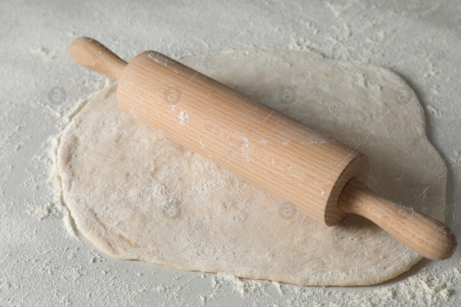 Photo of Raw dough and rolling pin on table