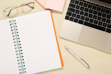 Photo of Empty notebook, laptop and stationery on wooden table, flat lay