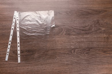 Photo of Punched pockets on wooden table, flat lay. Space for text