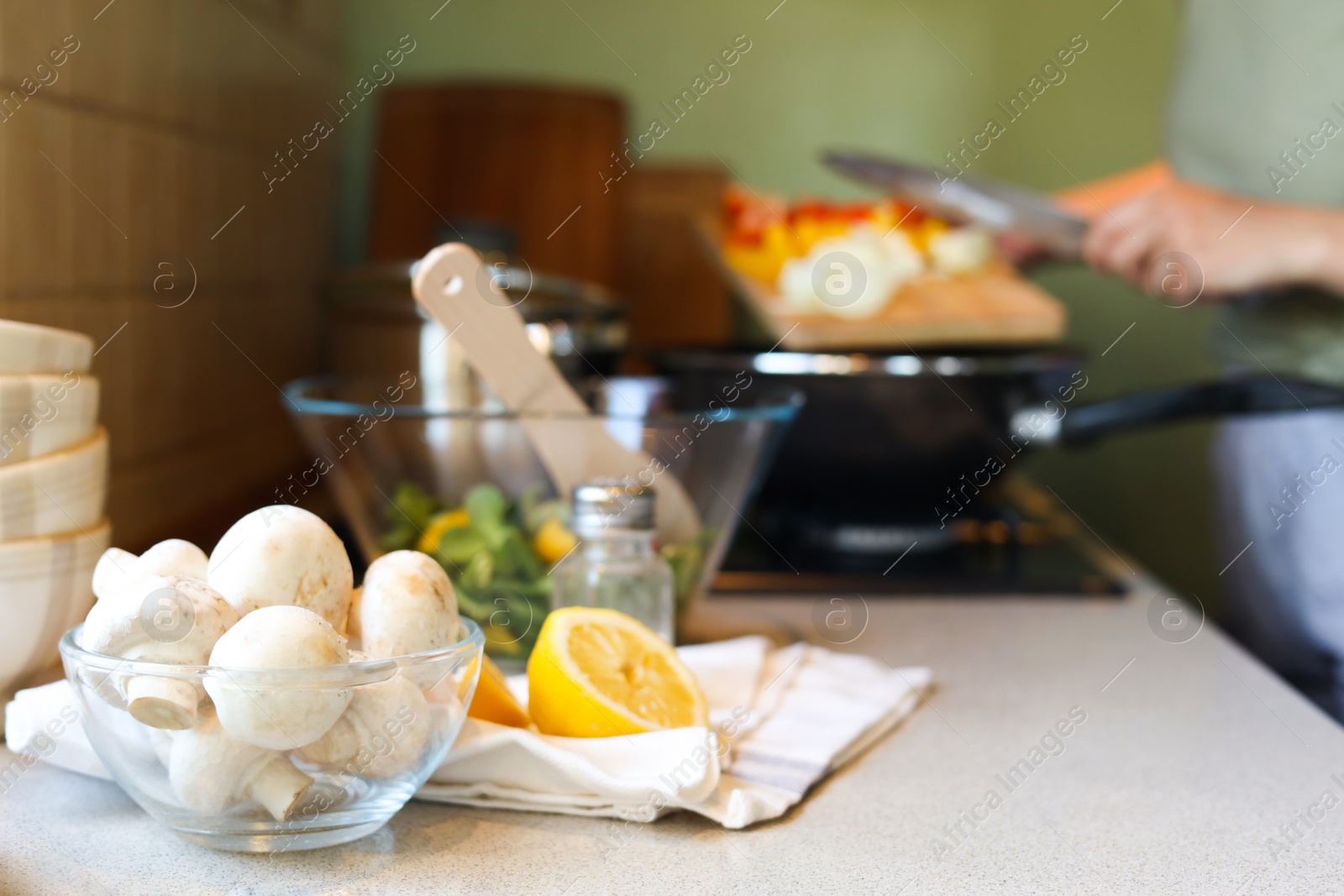 Photo of Woman cooking in kitchen, focus on bowl with mushrooms