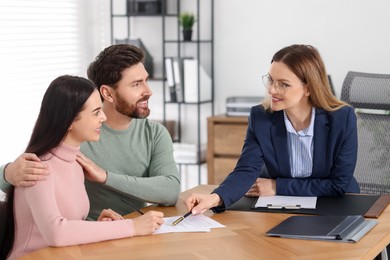 Photo of Happy couple signing document in lawyer's office