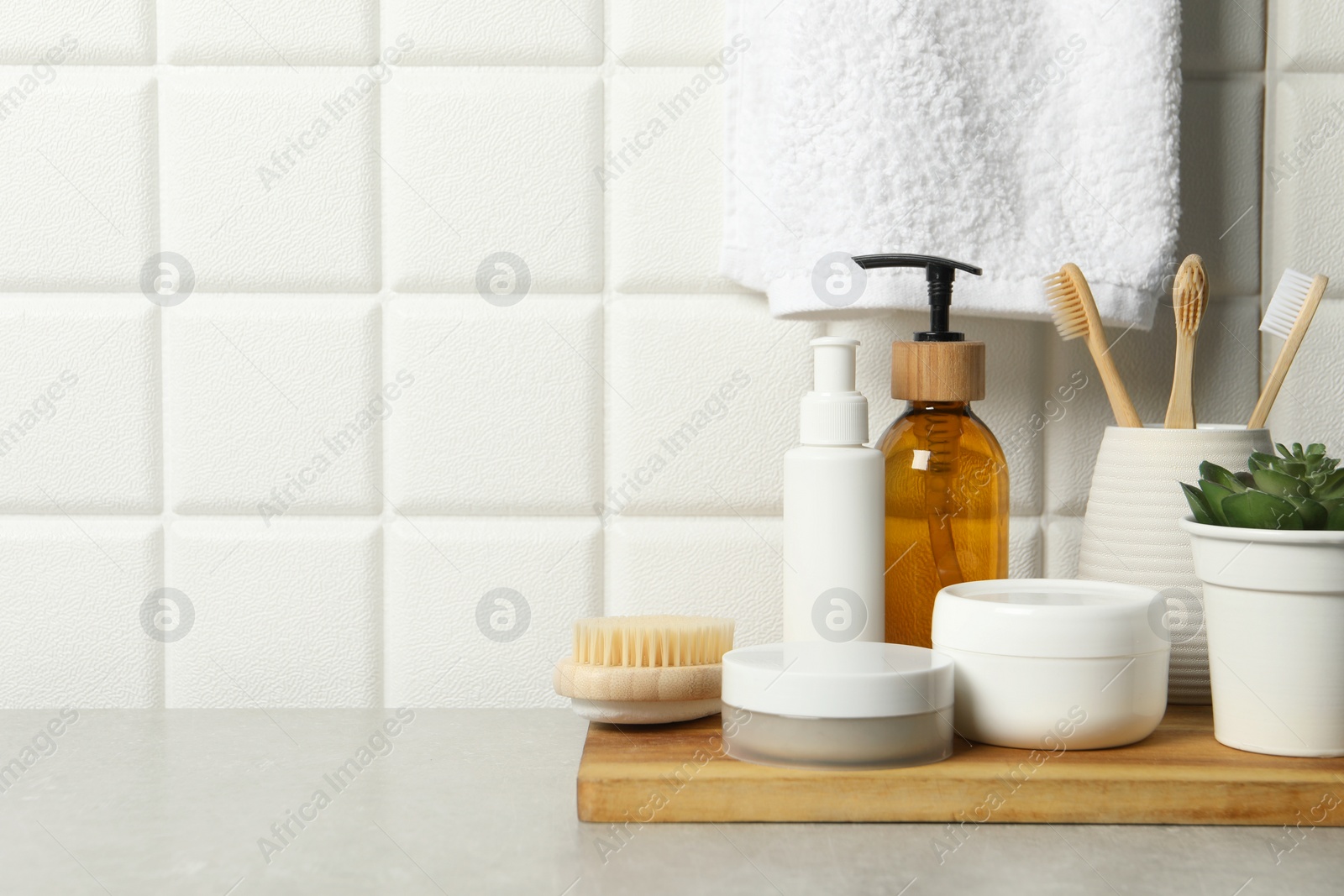 Photo of Different bath accessories and personal care products on gray table near white tiled wall, space for text