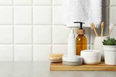 Different bath accessories and personal care products on gray table near white tiled wall, space for text