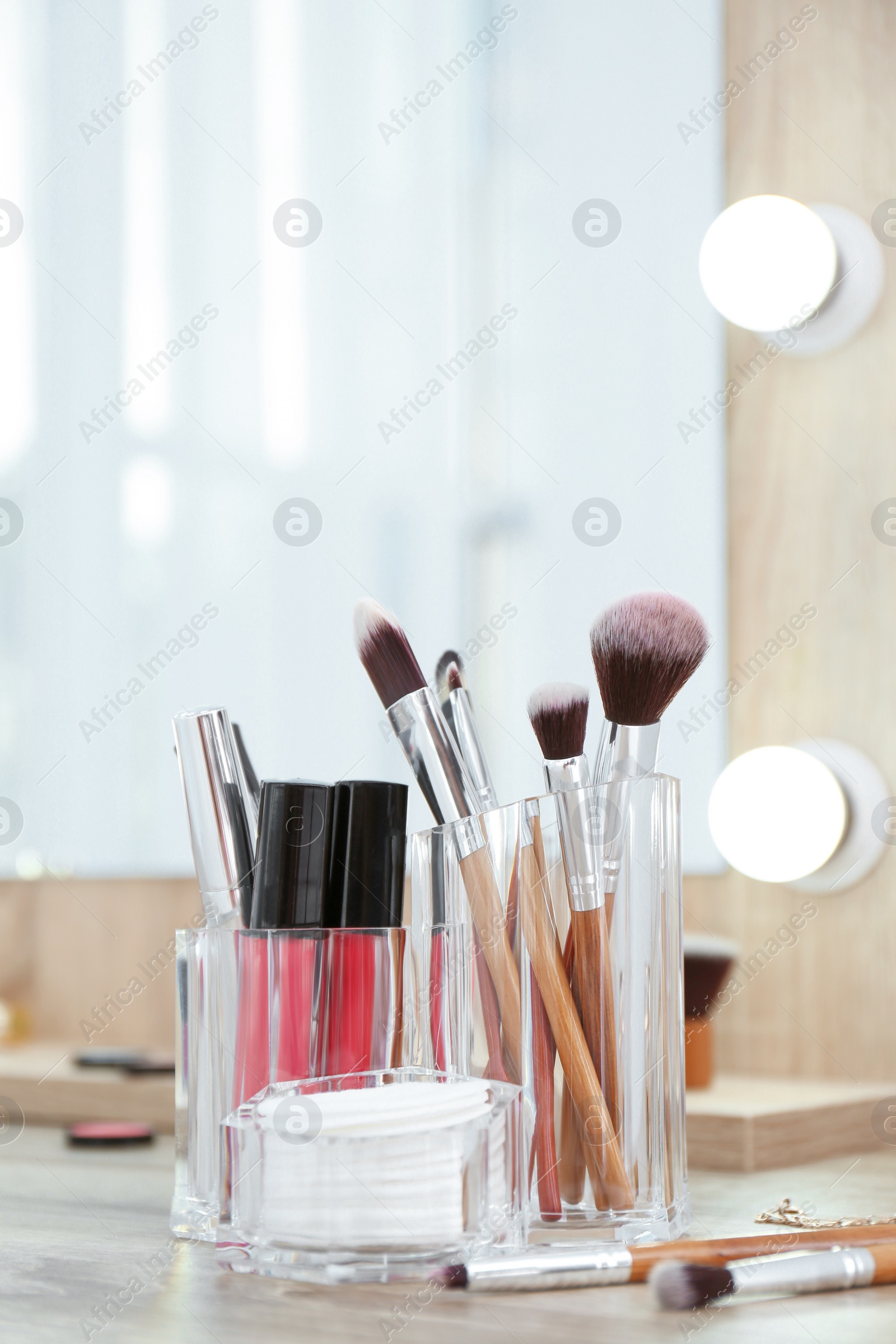 Photo of Organizer with cosmetic products for makeup on table near mirror