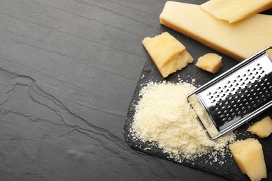 Photo of Whole and grated parmesan cheese on black table, flat lay. Space for text