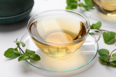 Cup of aromatic herbal tea with mint on white table