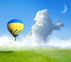 Image of Fantastic dreams. Hot air balloons in blue sky with clouds and crescent moon over misty green meadow