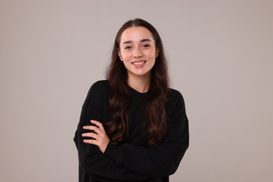 Beautiful young woman in stylish warm sweater on grey background