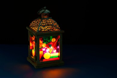 Photo of Decorative Arabic lantern on table against dark background. Space for text