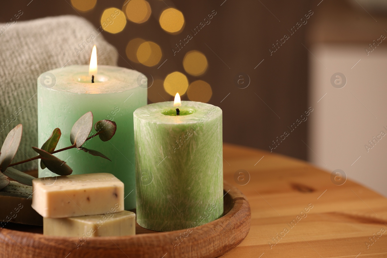 Photo of Spa composition. Burning candles, soap, towel and eucalyptus branch on wooden table, space for text