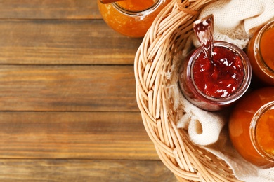 Photo of Jars with different sweet jam in wicker basket