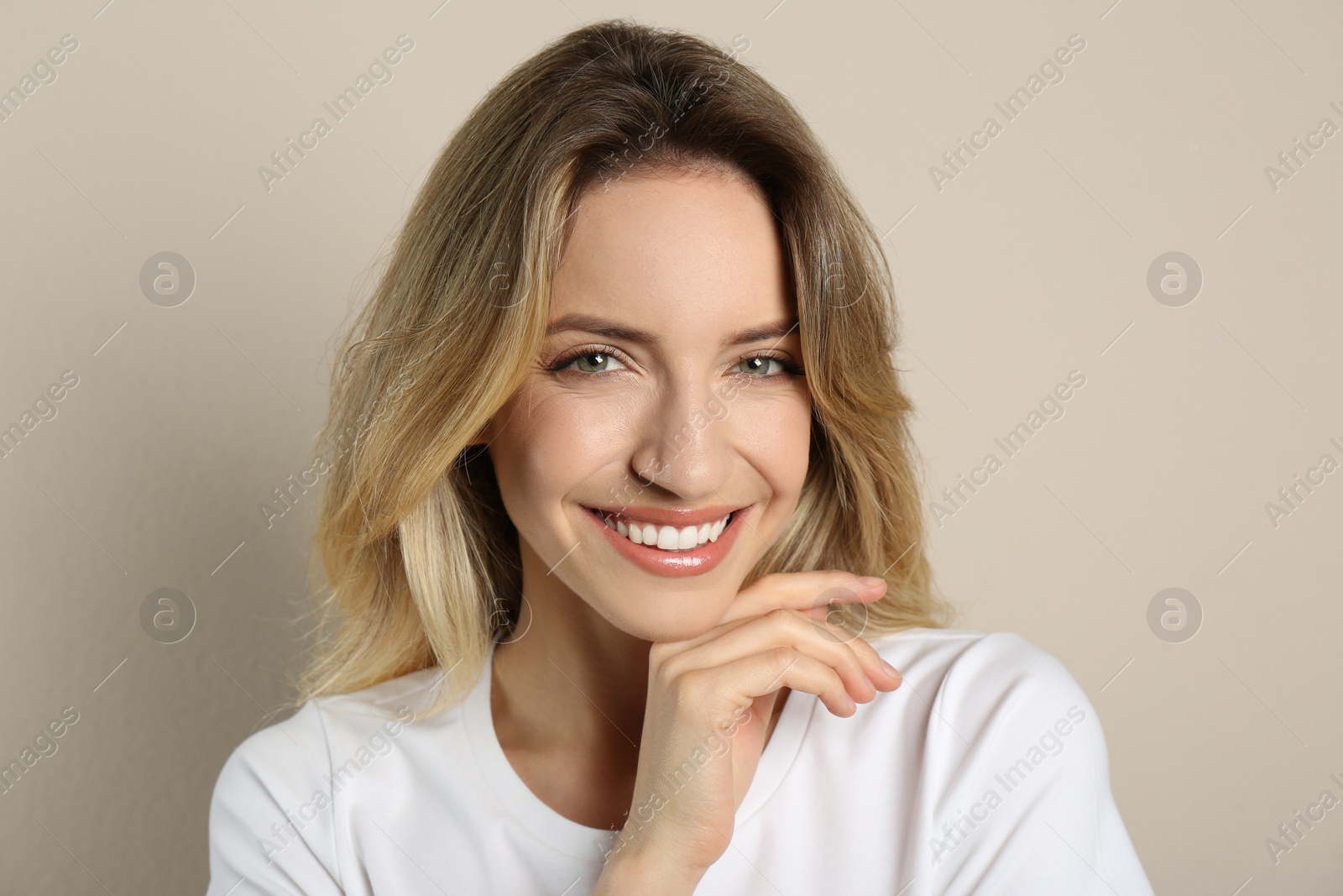 Photo of Portrait of happy young woman with beautiful blonde hair and charming smile on beige background