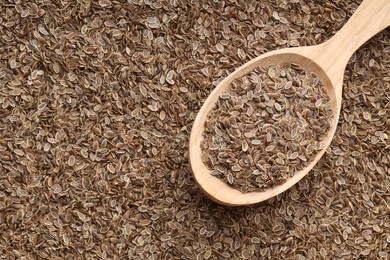 Photo of Dry dill seeds and wooden spoon, top view. Space for text