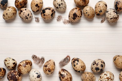 Flat lay composition with quail eggs on white wooden table. Space for text