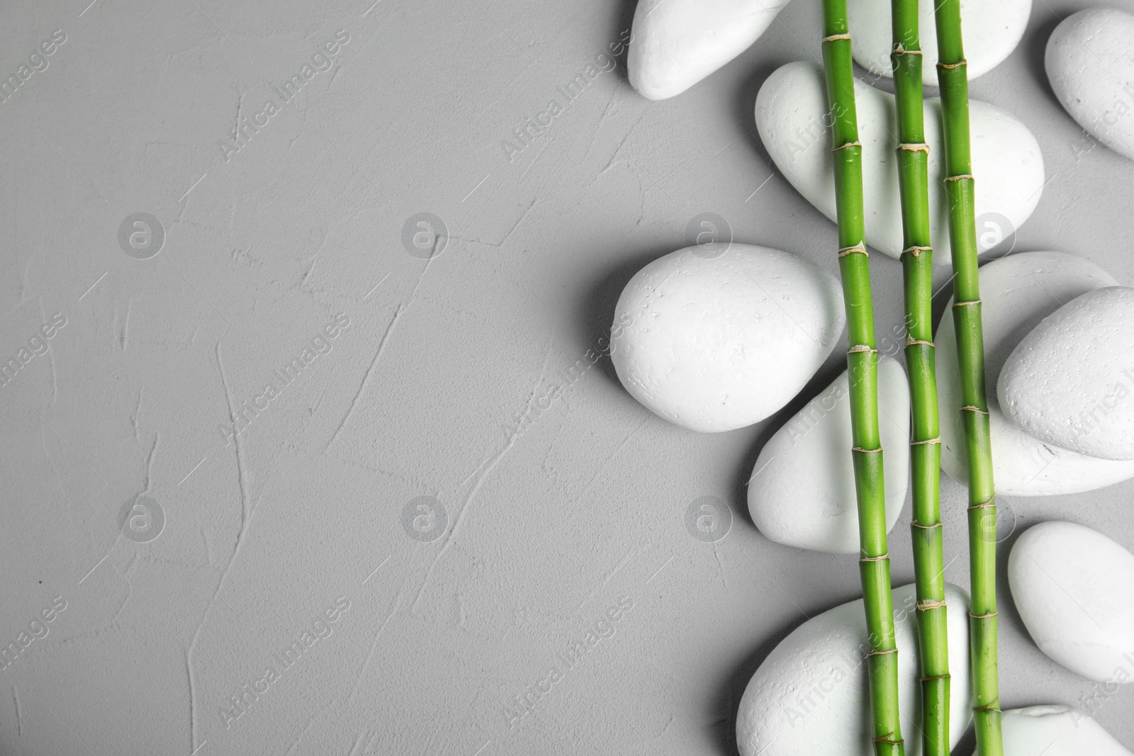 Photo of Zen stones and bamboo on grey background, top view with space for text