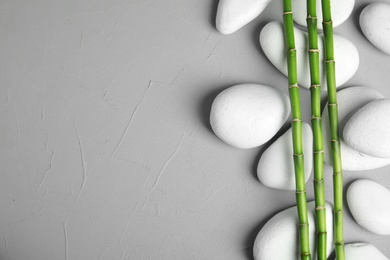 Photo of Zen stones and bamboo on grey background, top view with space for text