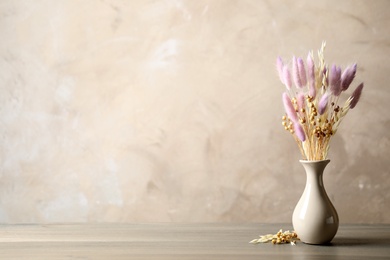 Photo of Dried flowers in vase on table against light grey background. Space for text